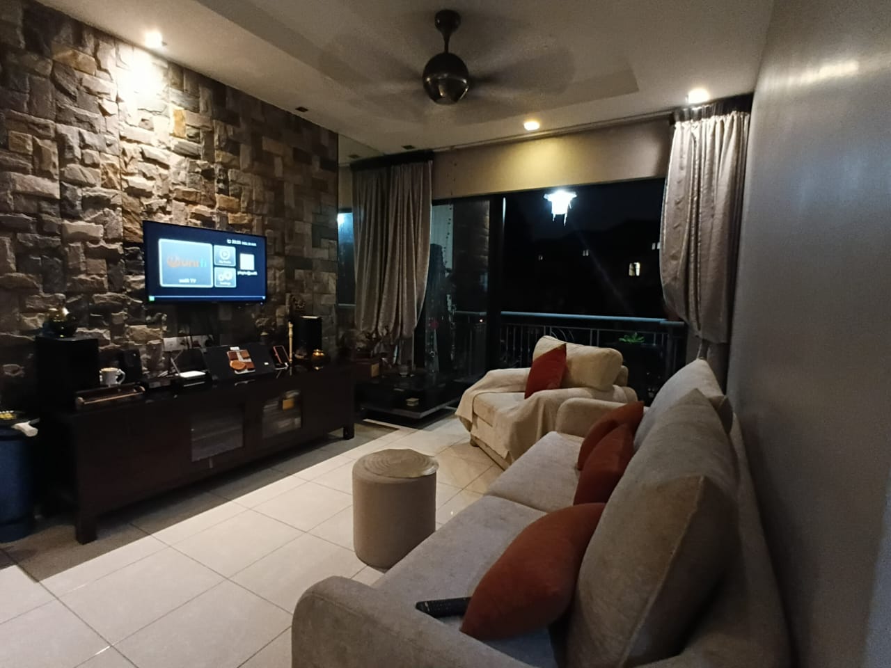 Living room with stone feature wall and balcony doors at Casa Indah 1